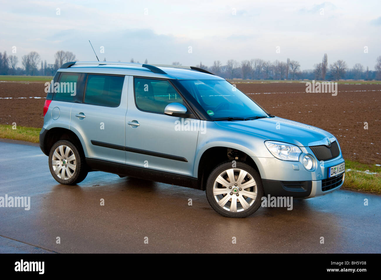 Front, side view Skoda Yeti SUV, 2010 model in light blue metallic parked on a street next to a field Stock Photo