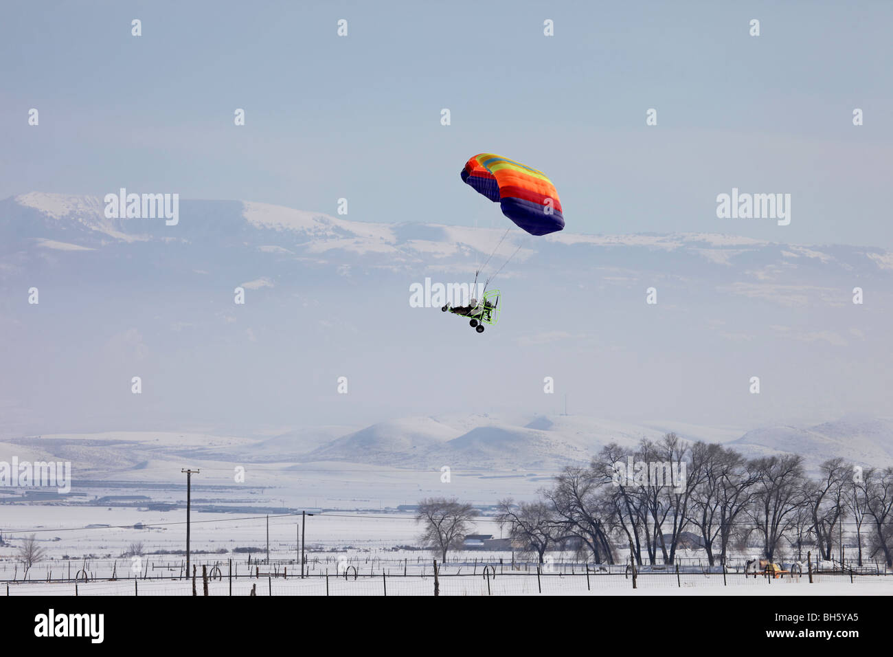 Powered parachute flying above rural farms. Multi colored parachute ...