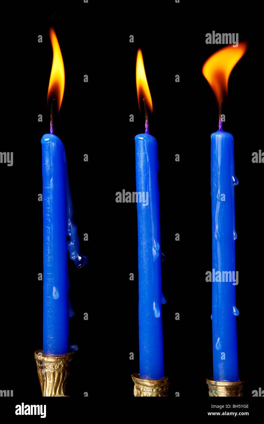 burning hanukkah candles in a menorah on black background Stock Photo