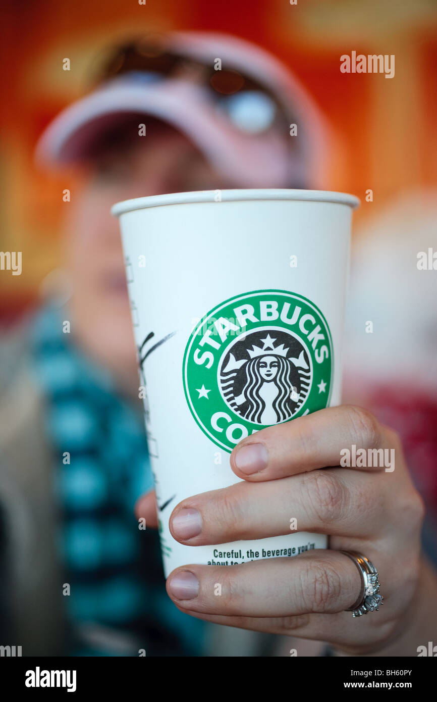 A person at a table, drinking a cup of Starbucks coffee Stock Photo