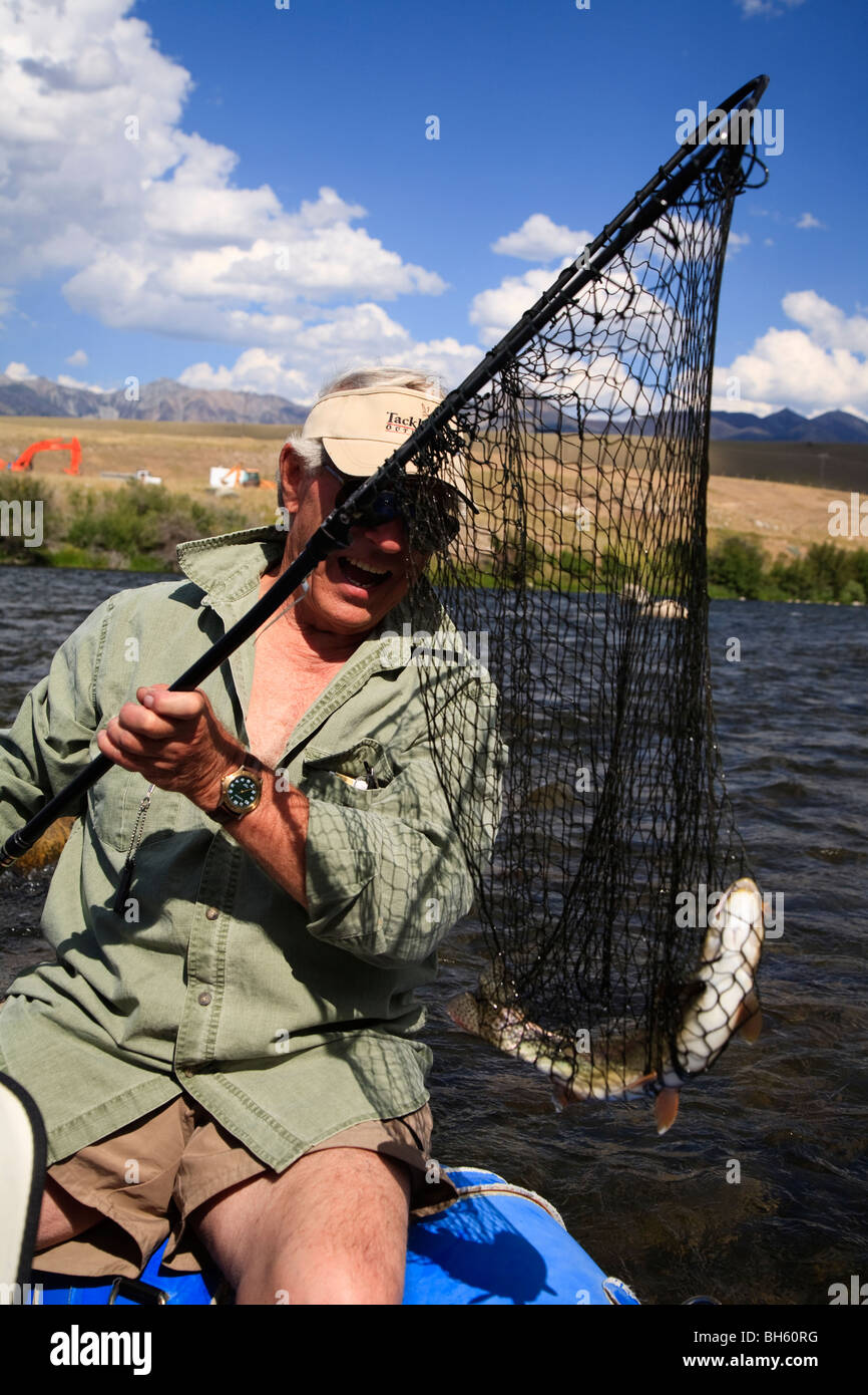 Fisherman catching a rainbow trout aboard a float boat on the Madison
