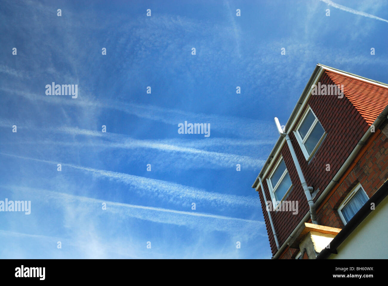 High altitude jet aircraft contrails filling the sky on a typical summer day in the UK Stock Photo