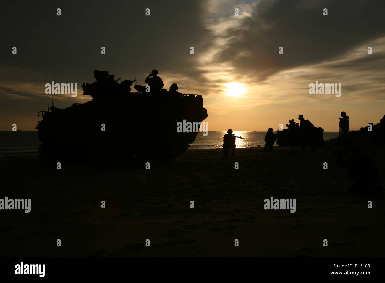 Silhouette of Marines and an amphibious assault vehicle providing security on Hwajin Beach, Republic of Korea. Stock Photo