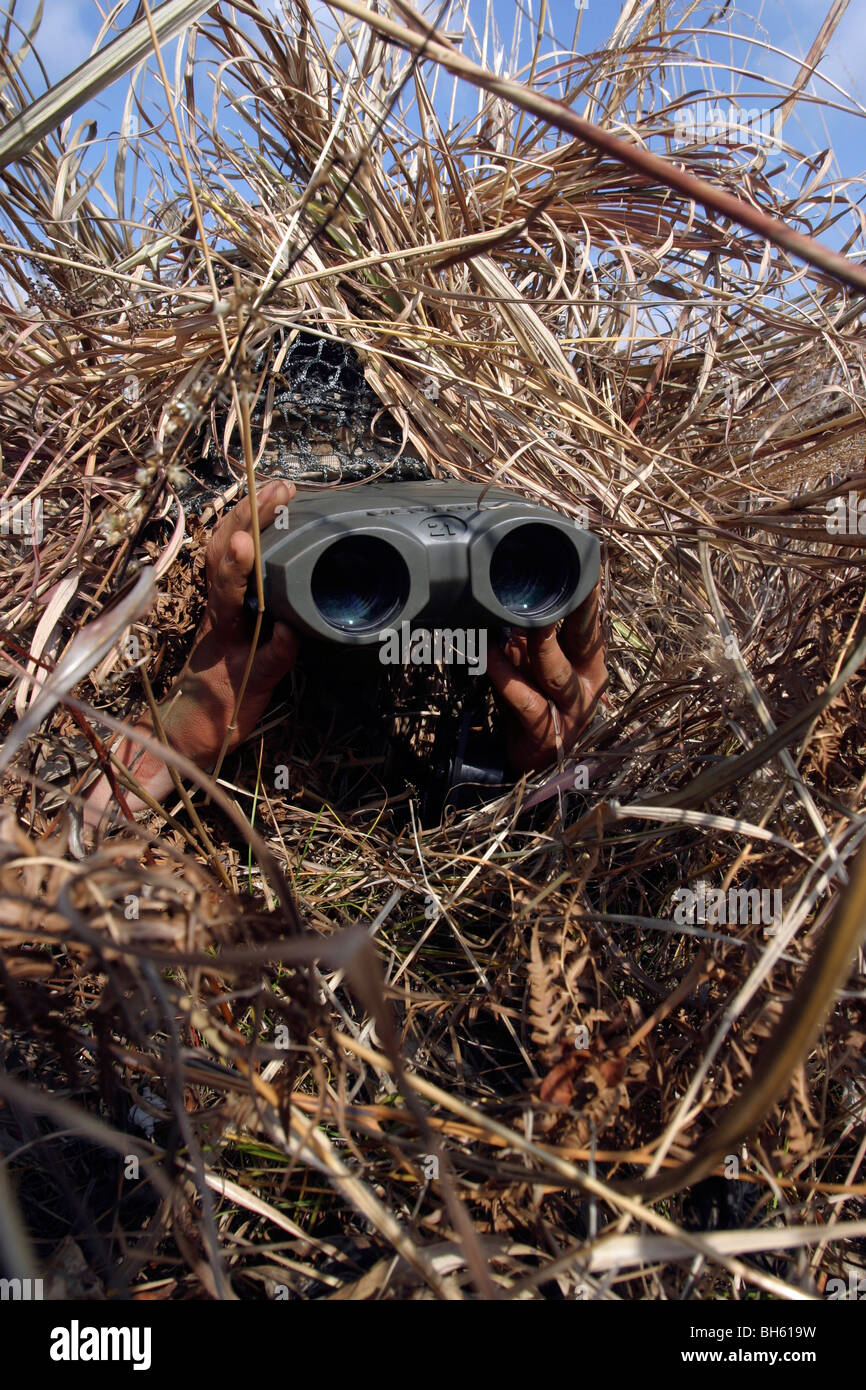 A scout observer practices observation techniques using a homemade ghillie suit. Stock Photo