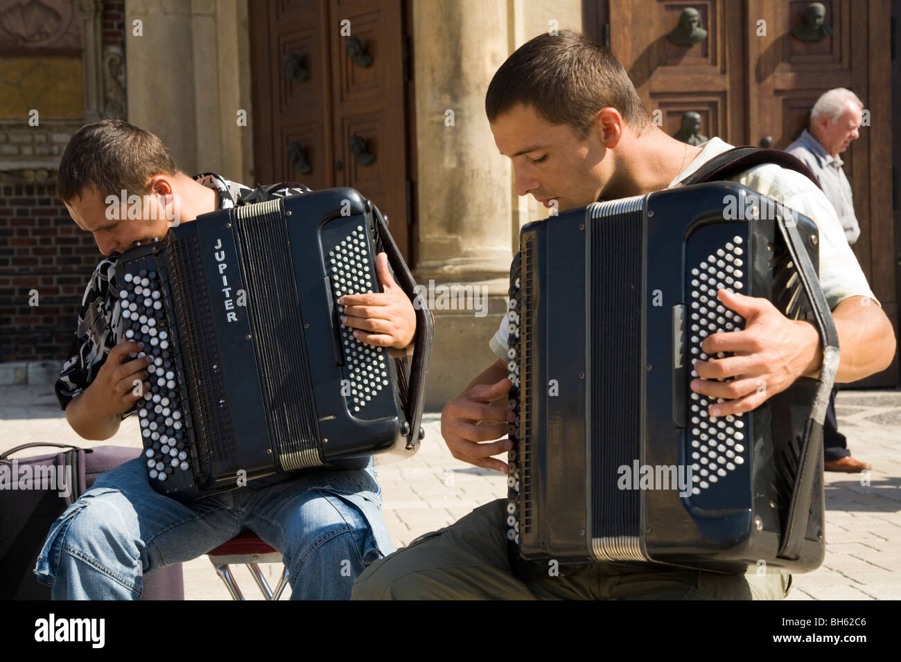 Buskers playing the accordion outside St Marys Basilica. Main Square, Krakow. Poland. Stock Photo