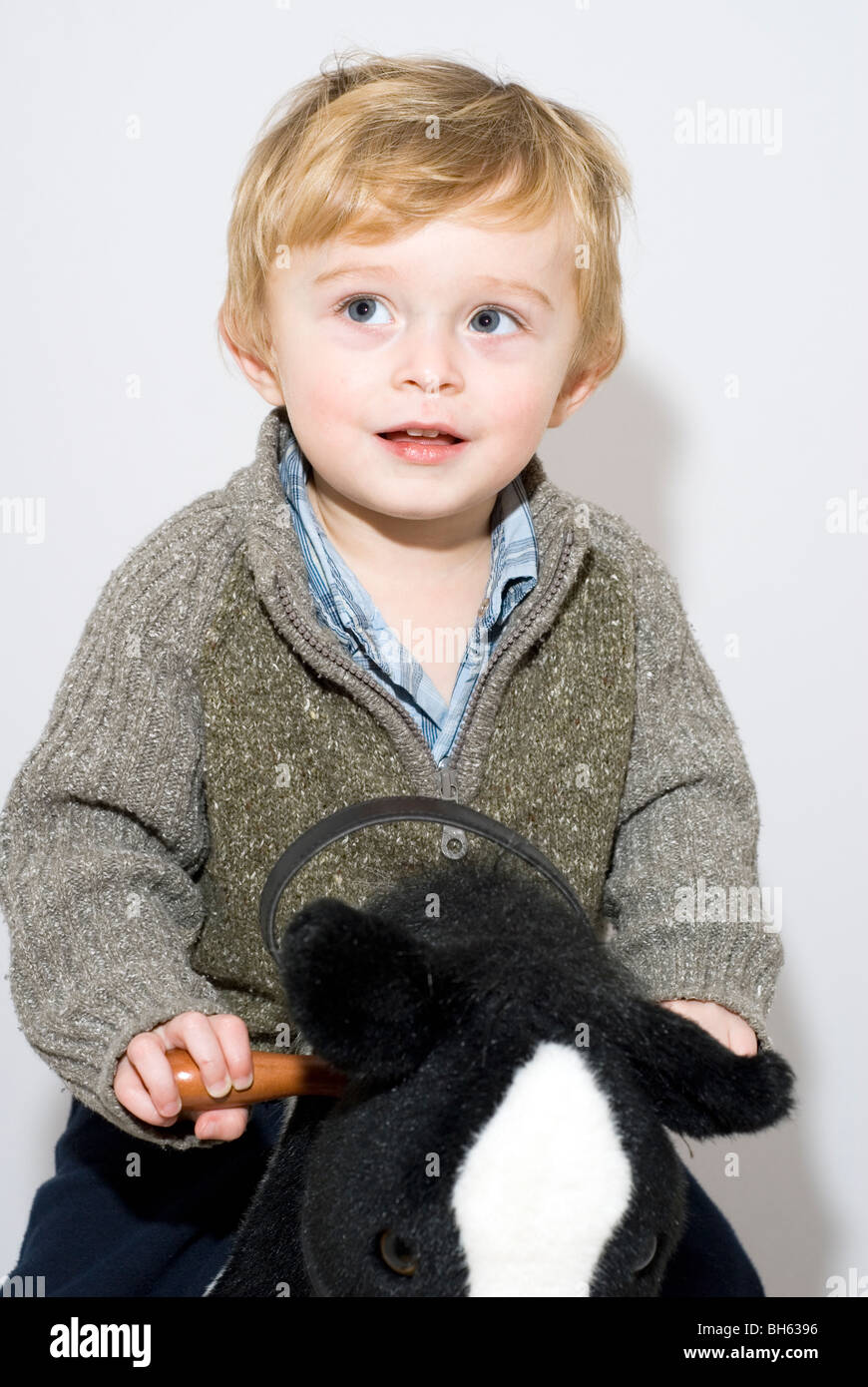 Portrait of Toddler Boy Aged 20 Months Riding on Rocking Horse Isolated on White Stock Photo