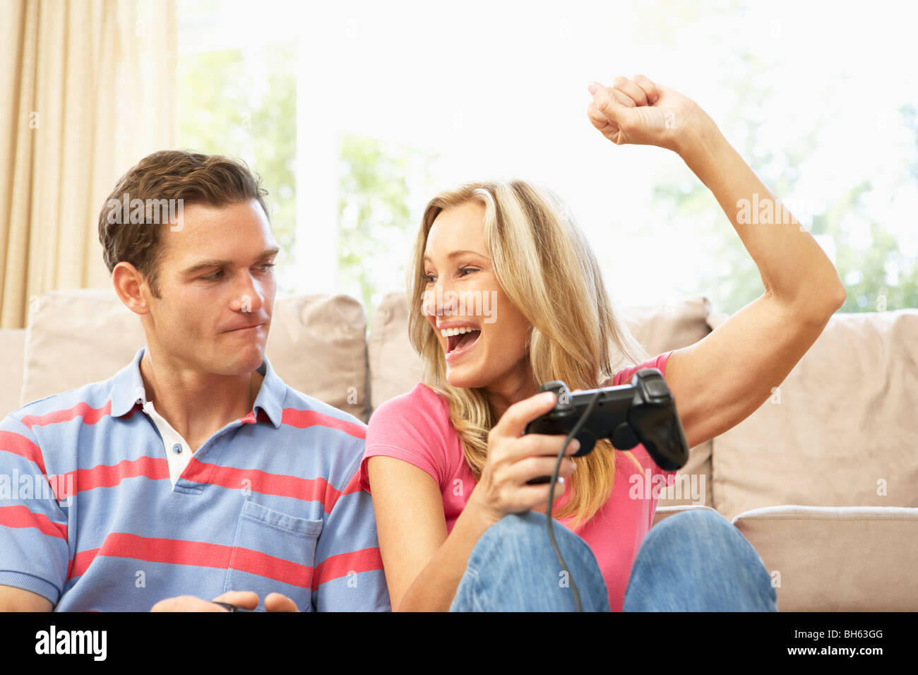 Young Couple Playing Computer Game On Sofa At Home Stock Photo