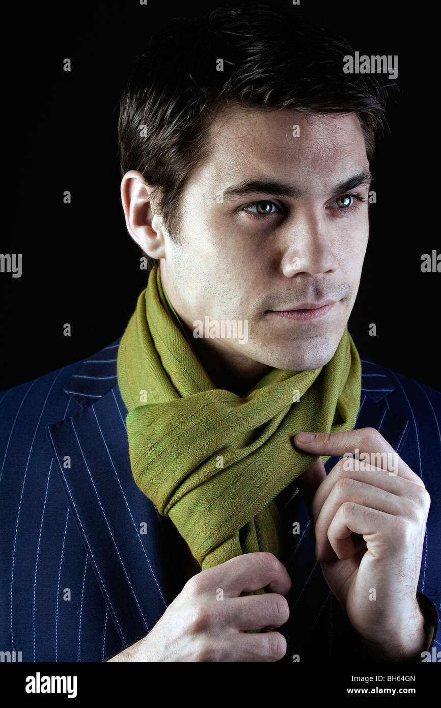 low key dramatic handsome man ties his scarf Stock Photo