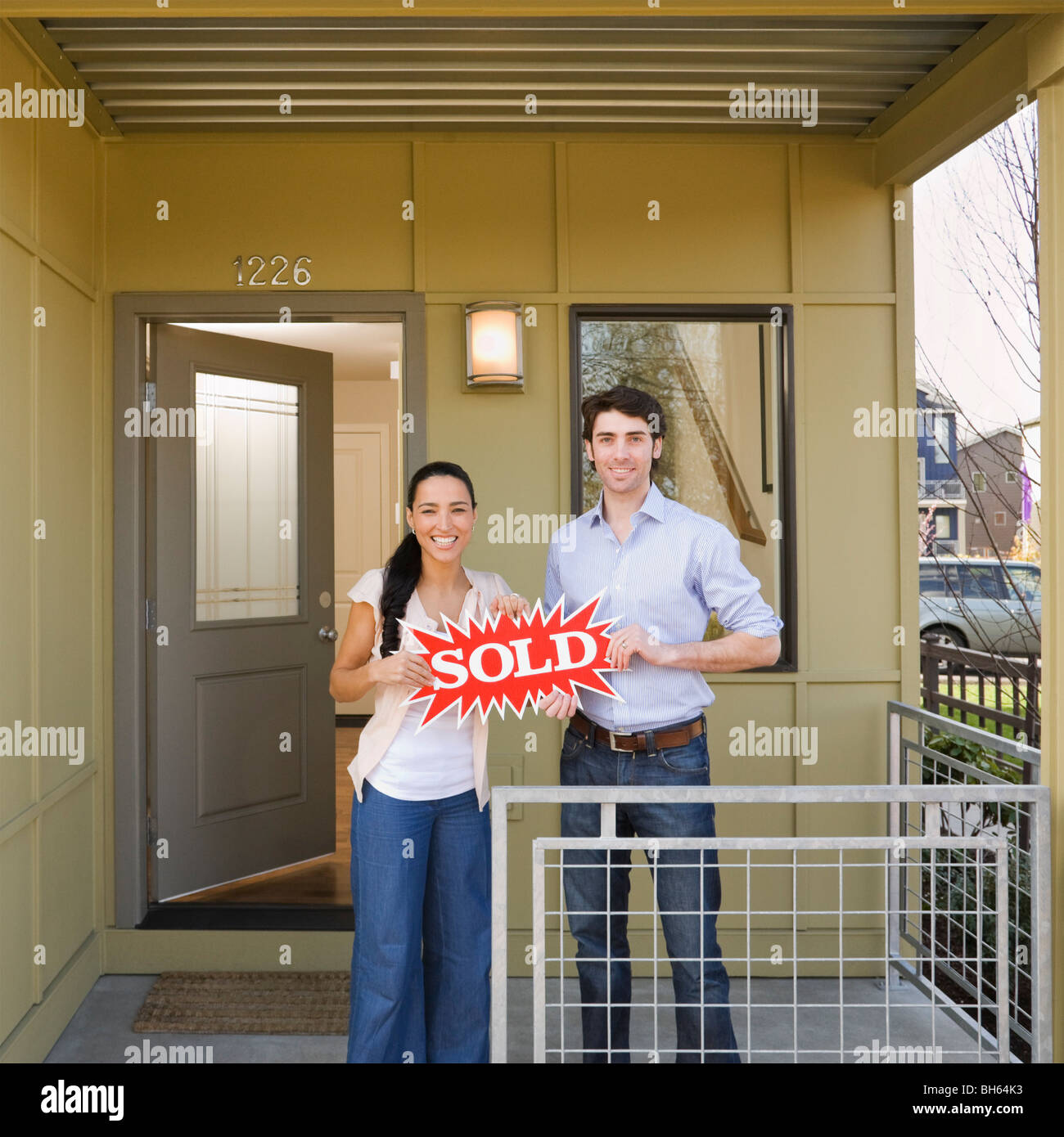 couple on front porch with sold sign Stock Photo - Alamy