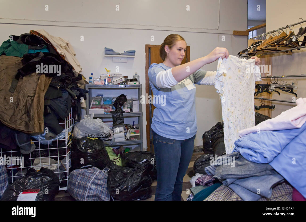Volunteer Sorts Donated Clothing at Thrift Shop Stock Photo