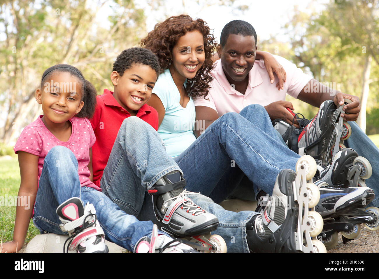 Family Putting On In Line Skates In Park Stock Photo