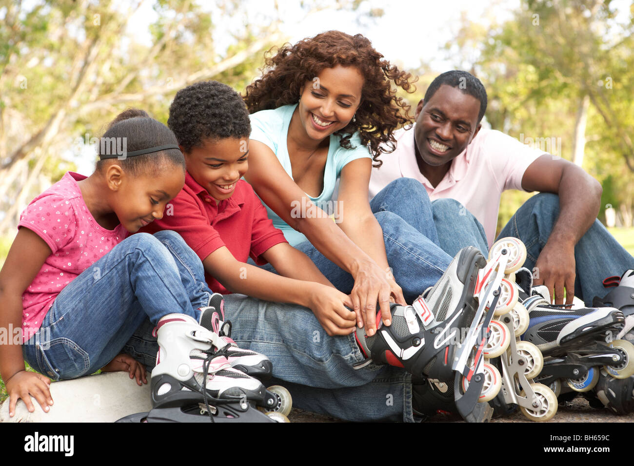 Family Putting On In Line Skates In Park Stock Photo