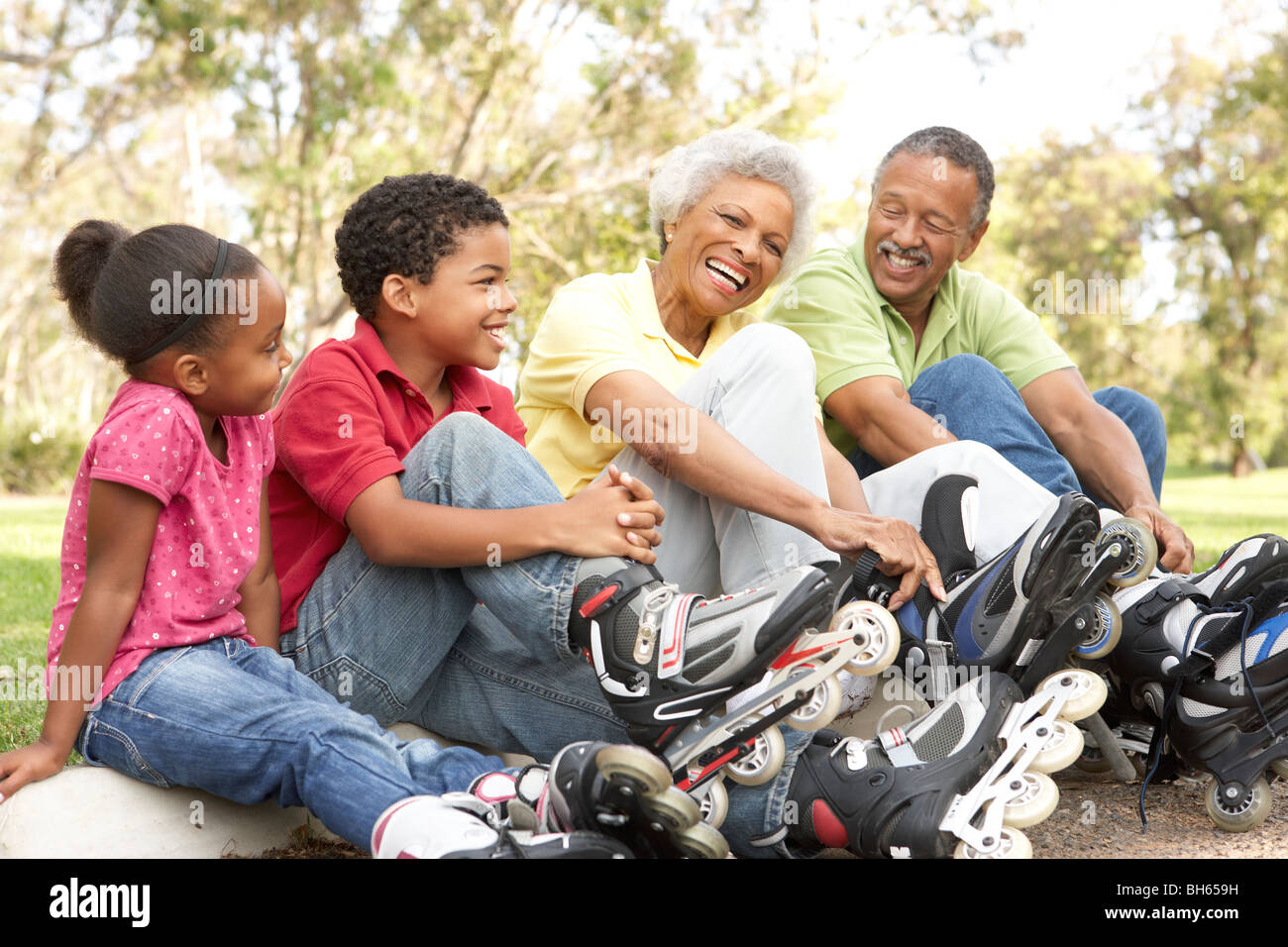 Grandparent With Grandchildren Putting On In Line Skates In Park Stock Photo