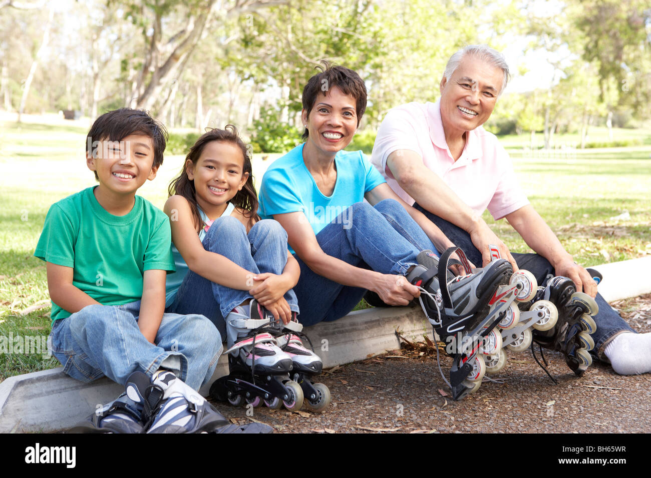 Grandparents With Grandchildren Putting On In Line Skates In Park Stock Photo