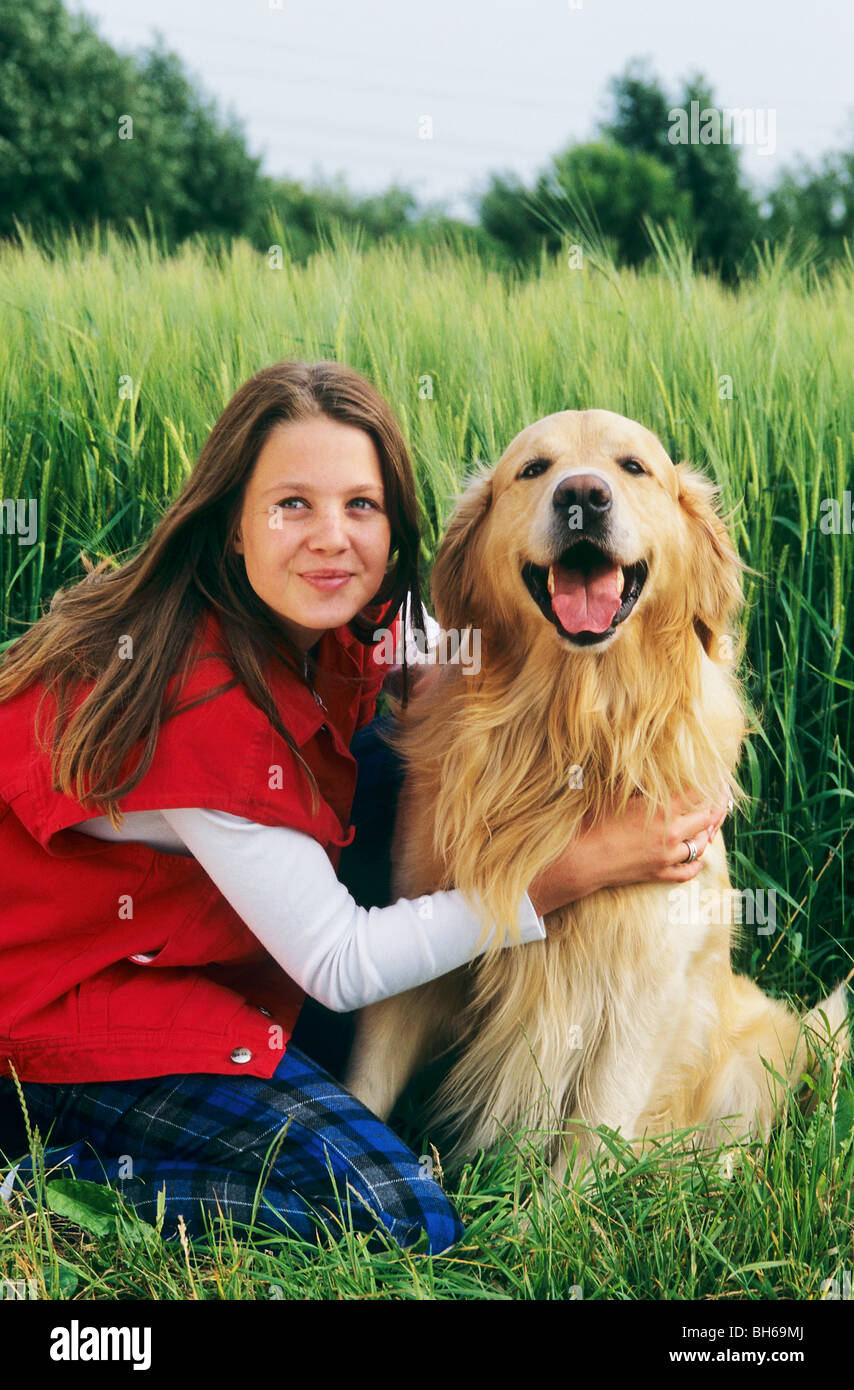 girl and a Golden Retriever dog - sitting in front of a cornfield Stock ...