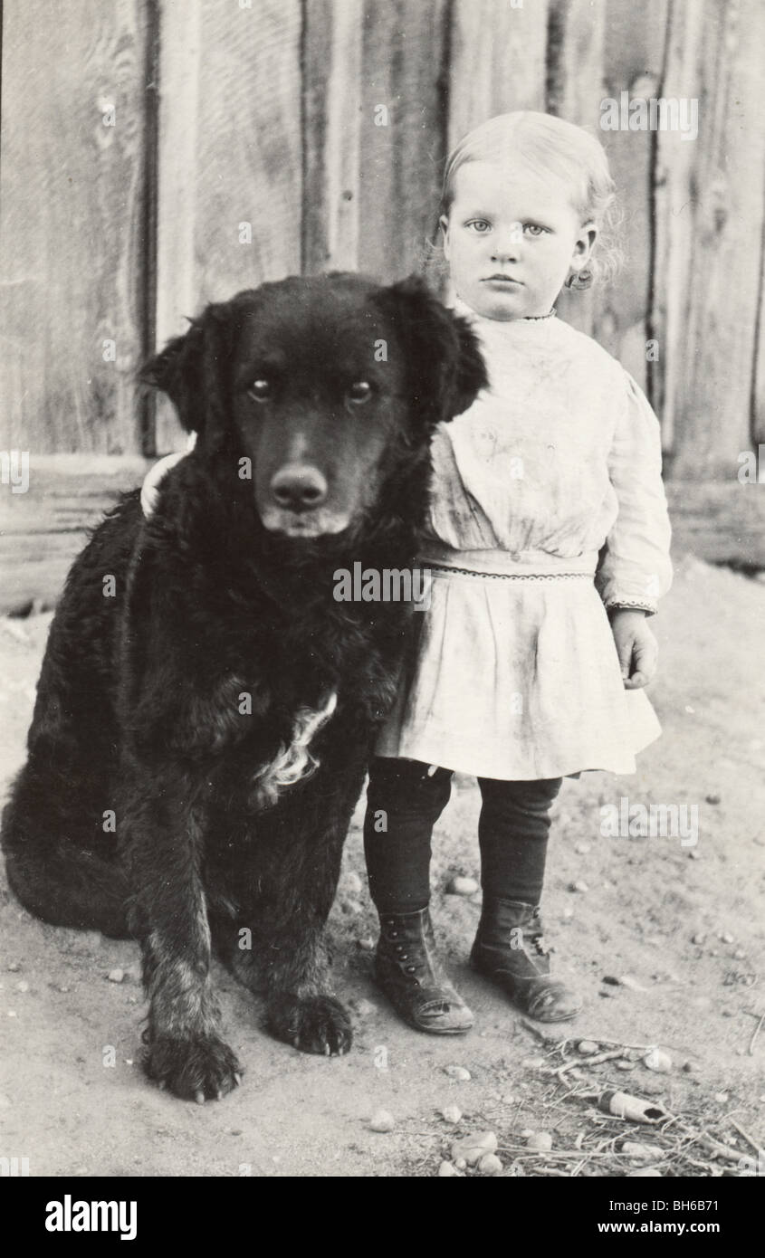 Little Girl Guarded by Huge Black Dog Stock Photo