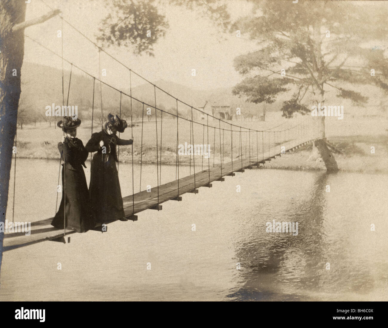 Two Women Standing on Suspended Footbridge Stock Photo