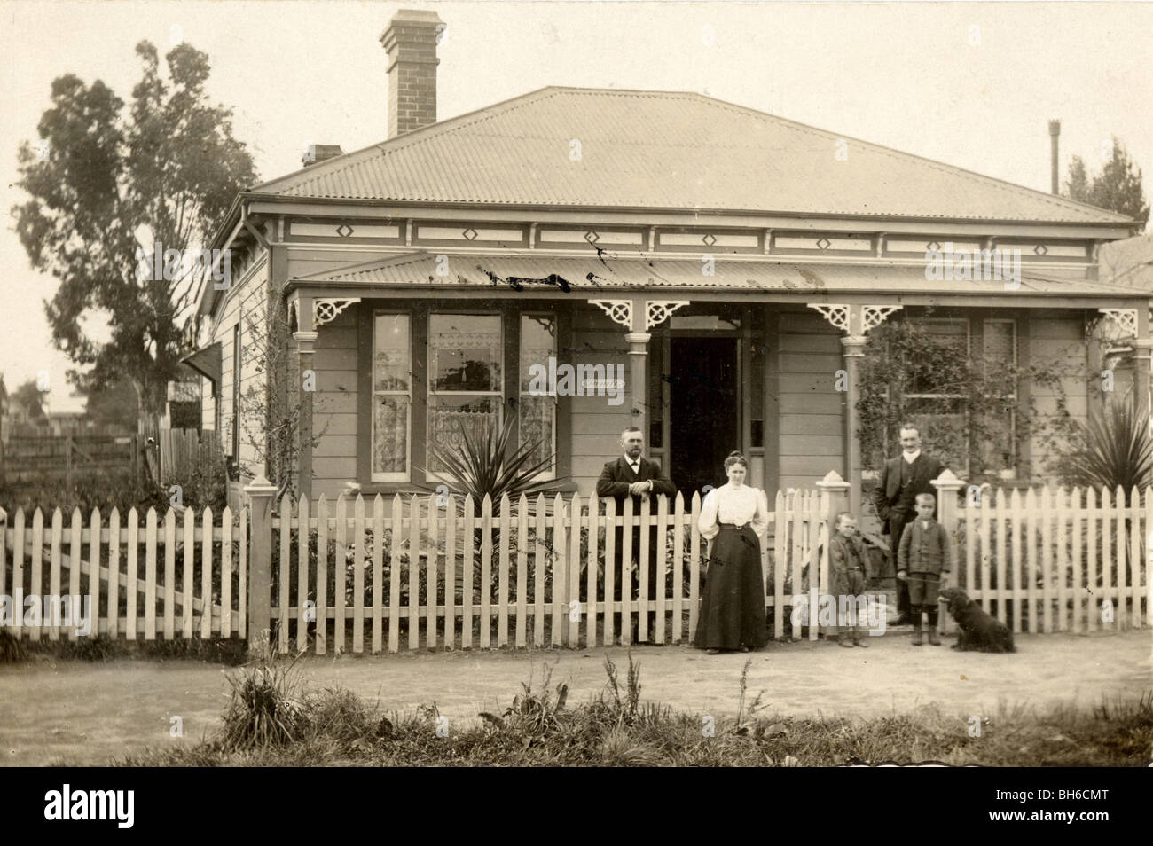 Family & Dog in front of Victorian Bungalow Stock Photo