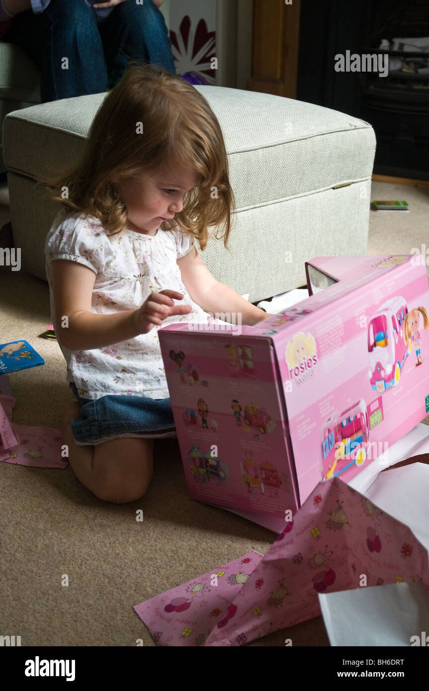 dh  GIRL UK 2 Two year old girl opening her pink wrapped birthday present young child childrens gift baby presents Stock Photo