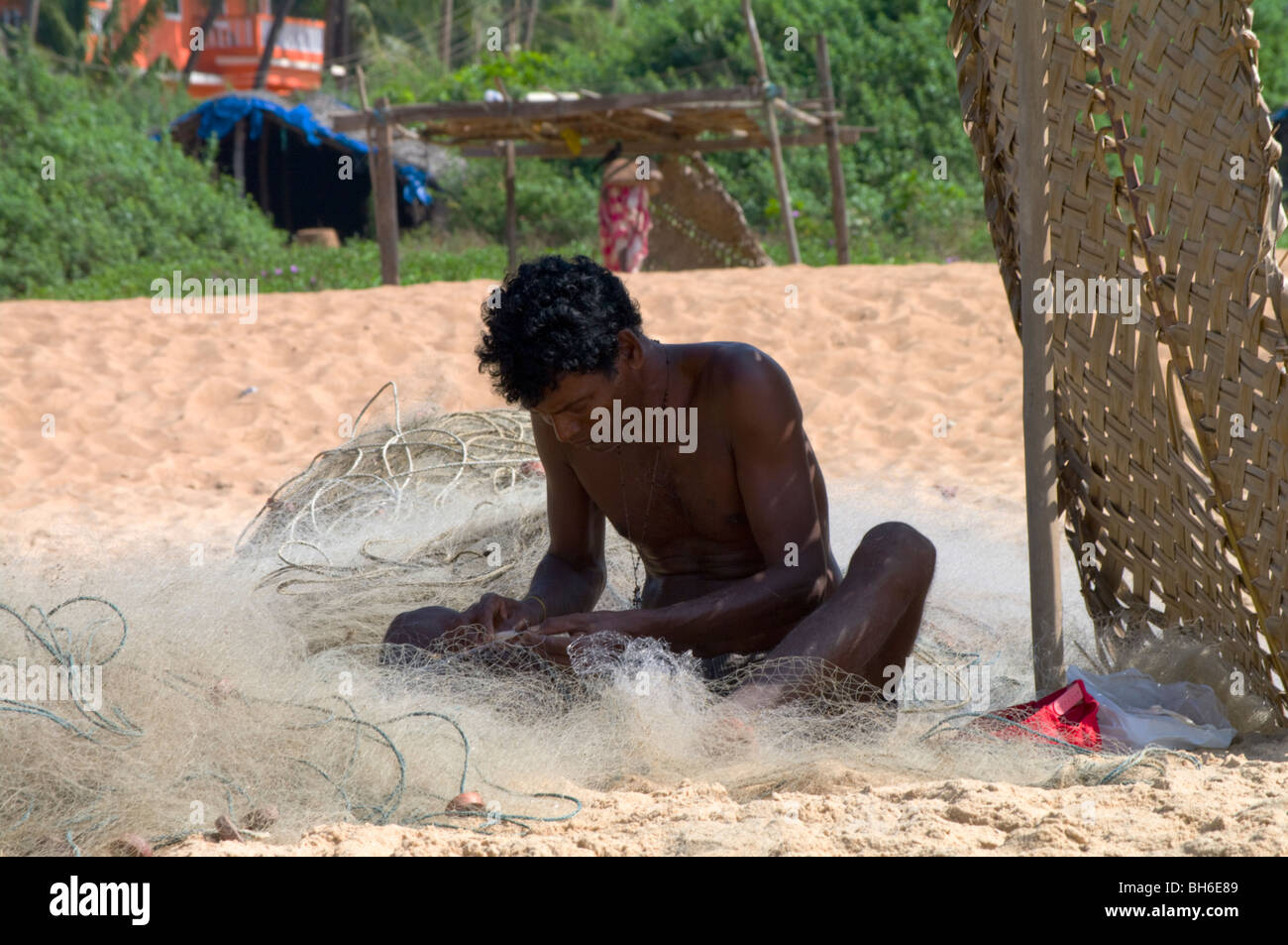Indian fisherman mending his nets on the beach in Goa Candolim Stock Photo