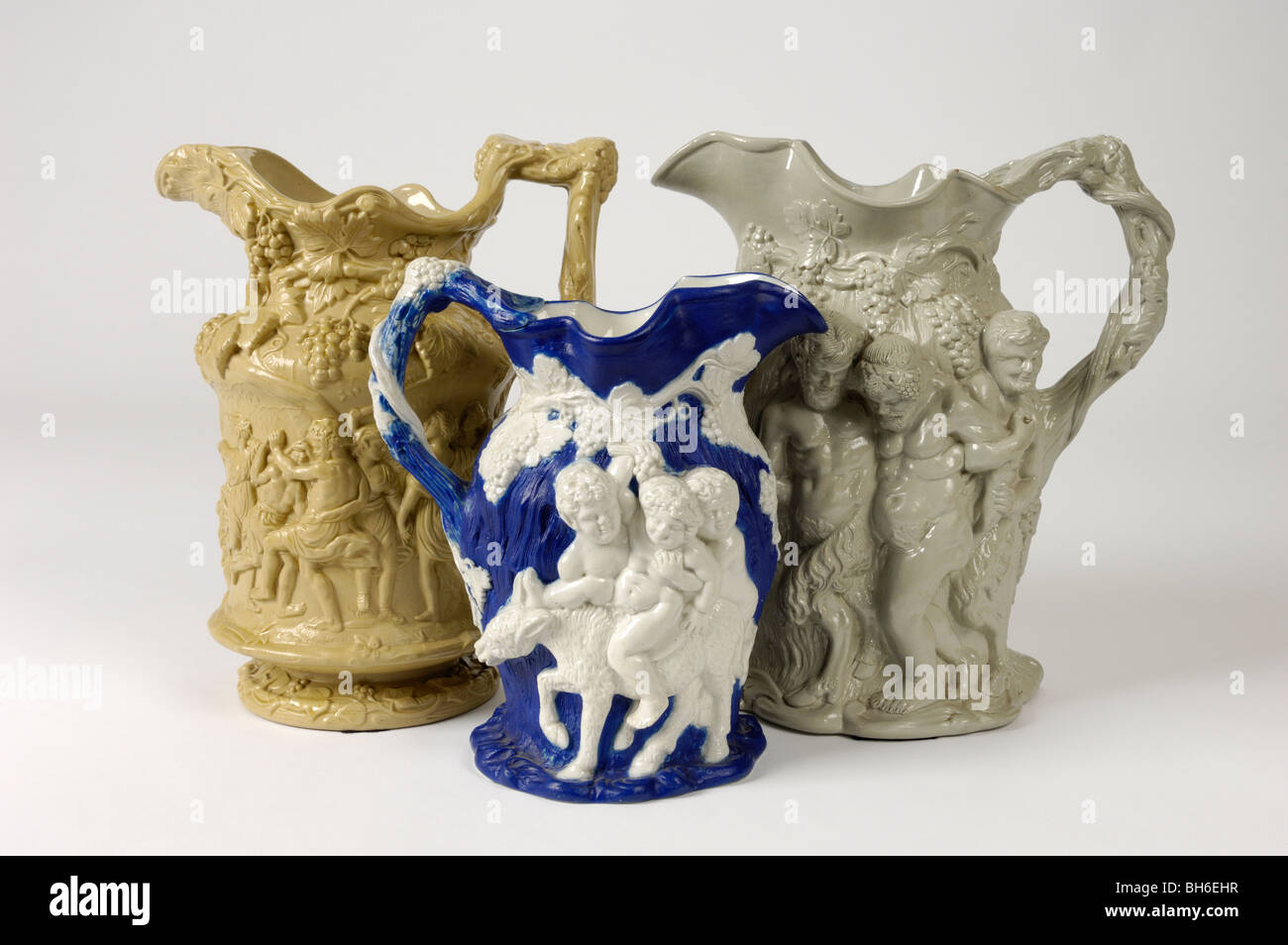Three antique 19th C. English stoneware relief moulded jugs with  Bacchanalian ornament. Figures: infant Bacchus, old Silenus. Stock Photo