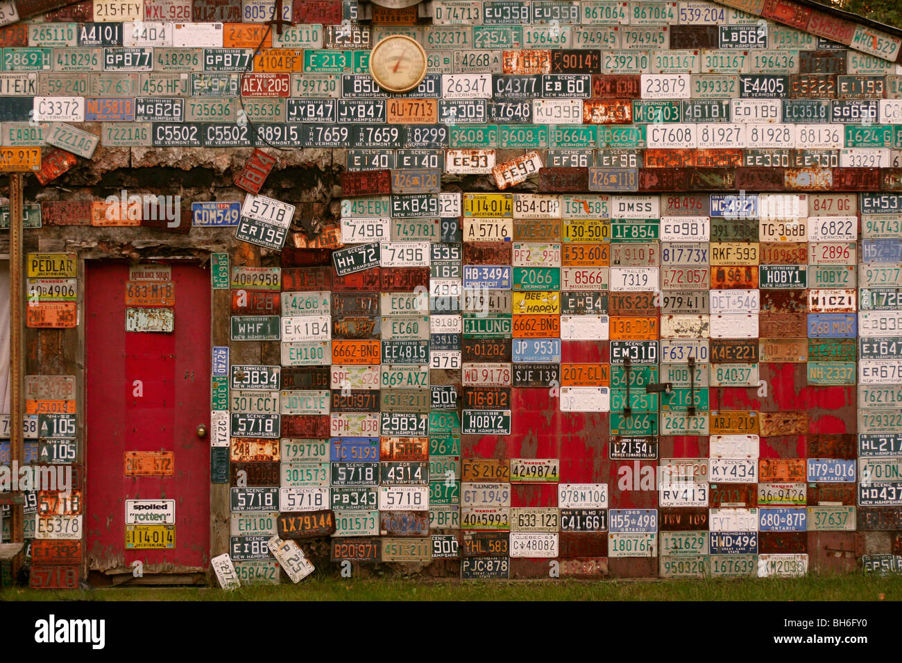 wall of metal car license plates on garage with red door Stock Photo