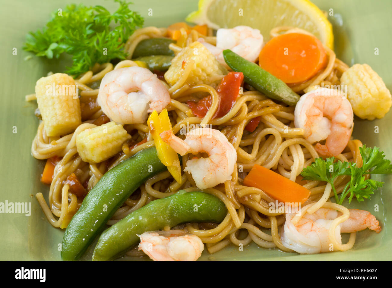 shrimp with stir fry noodles, baby corn, and green snap peas Stock Photo