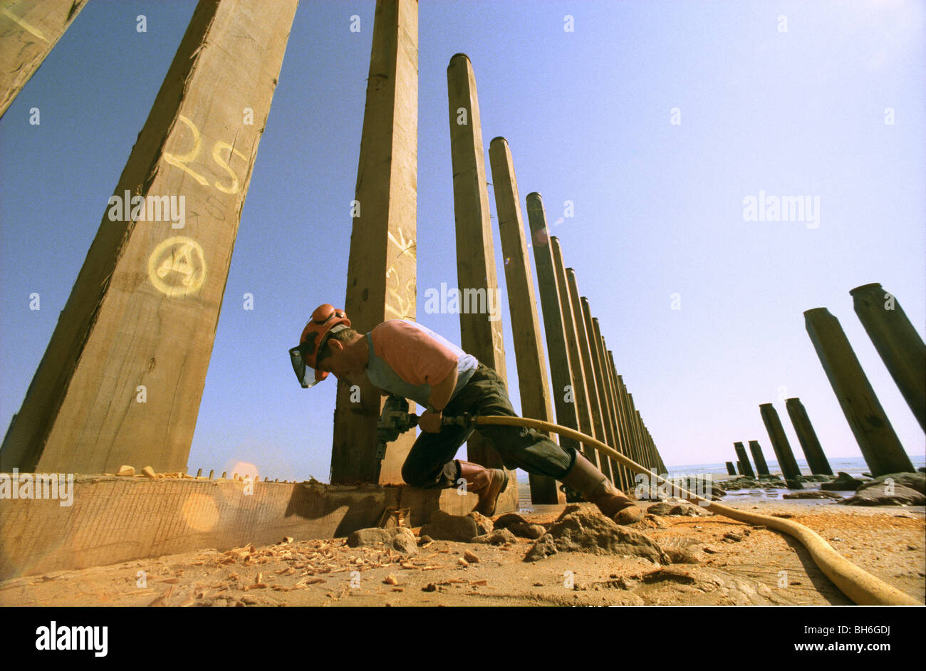 A workman putting up new sea defence groynes in Eastbourne, Sussex Stock Photo