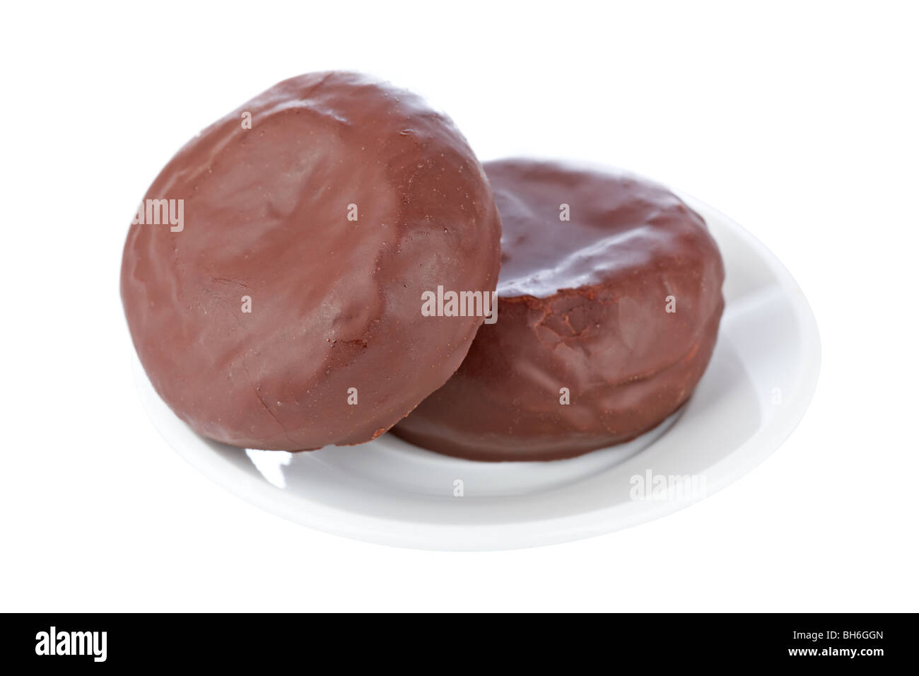 Two delicious chocolate donuts on a dish isolated on white background with shallow depth of field Stock Photo