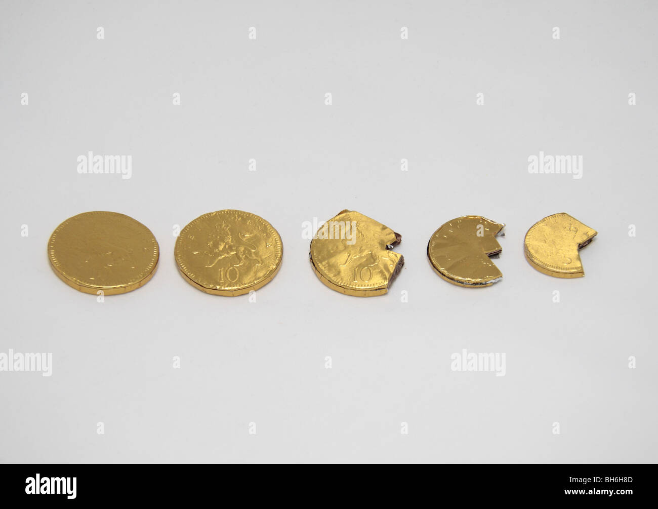 A line of slowly shrinking, disappearing chocolate coins symbolising depreciation, recession etc. Stock Photo