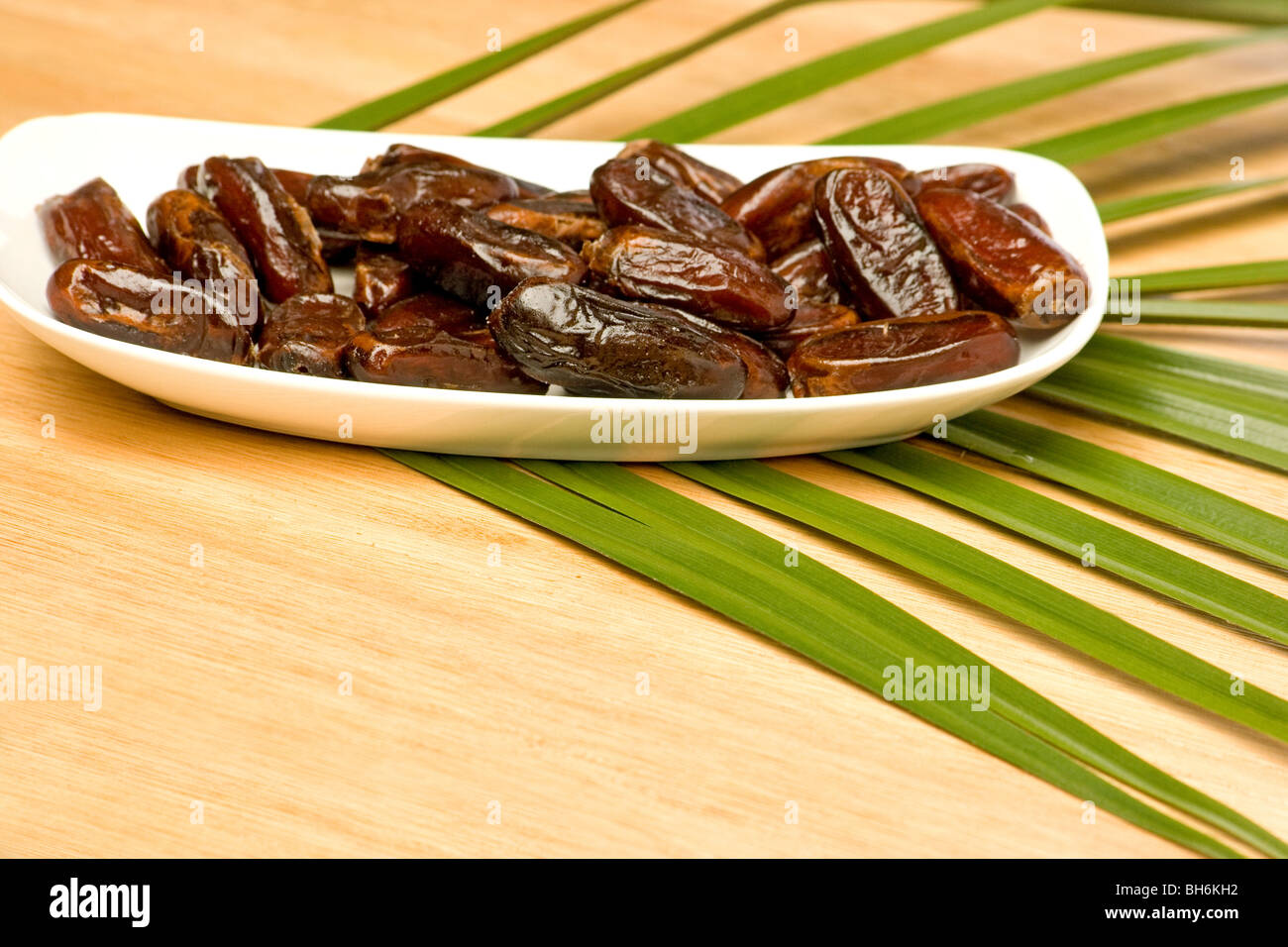 Close-up of dried dates and palm fronds on wooden  background Stock Photo