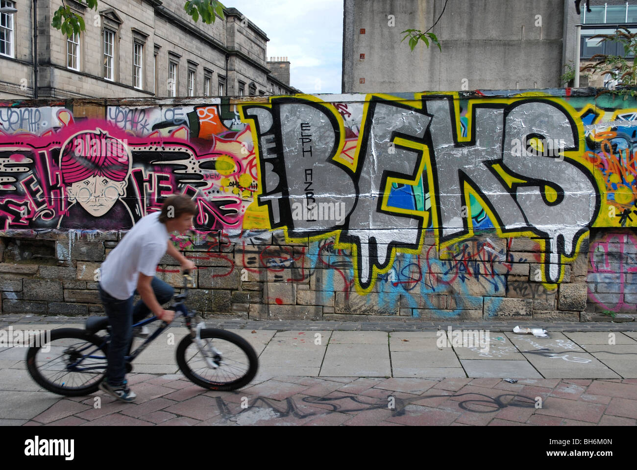 Boy on a bicycle and graffiti in Potterrow Edinburgh Stock Photo