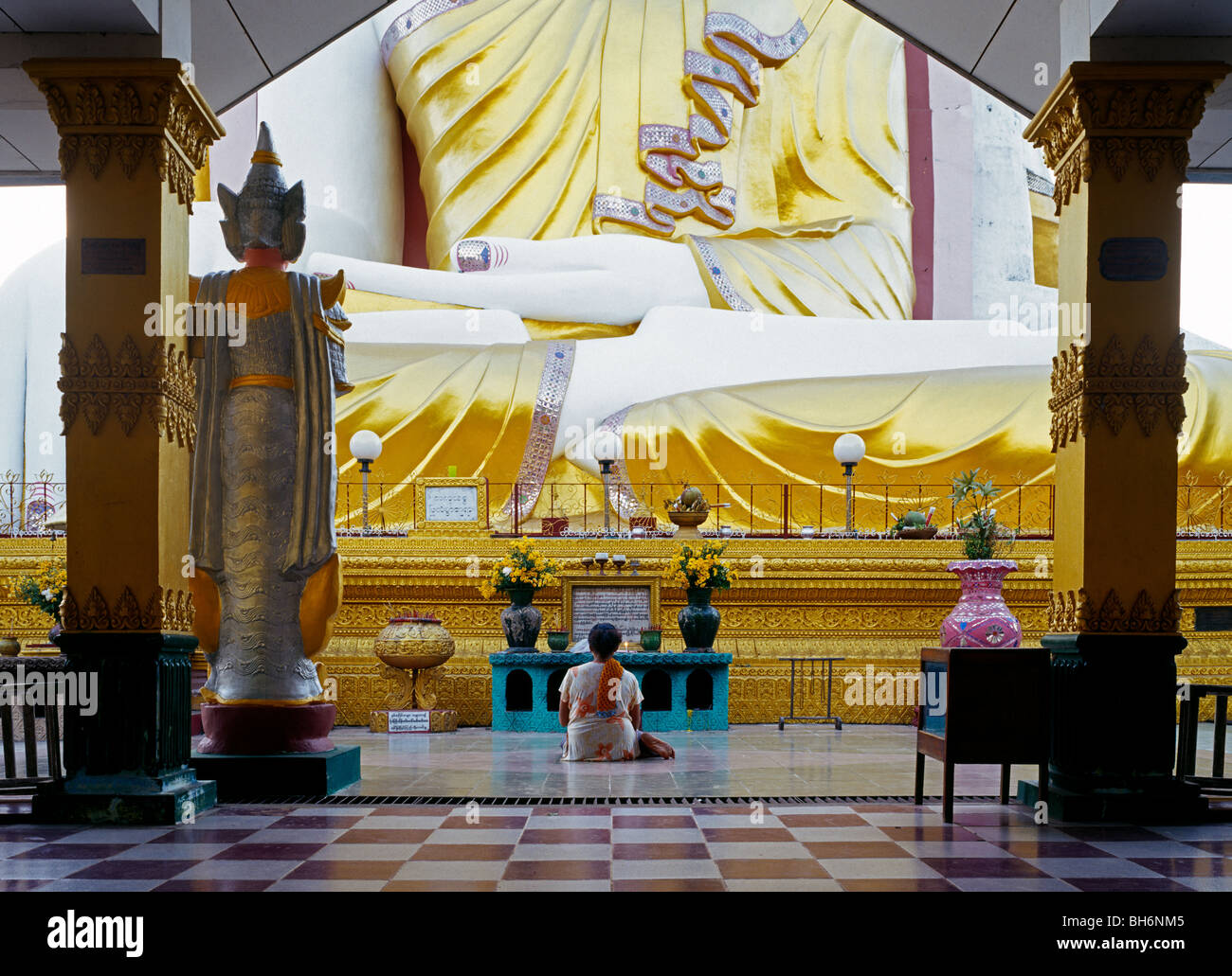Woman sitting and praying in front of Kyaik Pun Paya - Four Seated Buddhas shrine Myanmar Burma Stock Photo