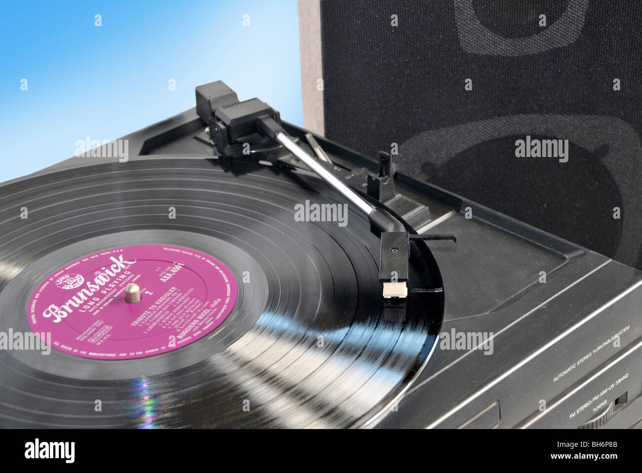 Looking down on an LP being played on a turntable with a speaker in the background. Stock Photo