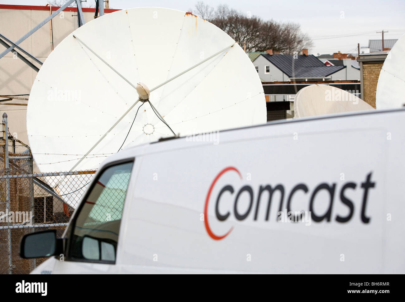 A Comcast Corporation logo on a vehicle in front of a satellite dish.  Stock Photo