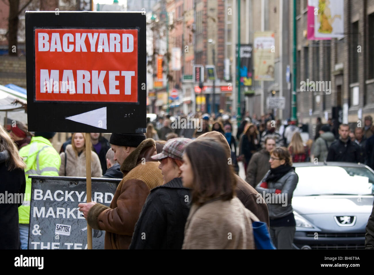 Trader holding a Backyard Market sign in Brick Lane, London E1. Stock Photo