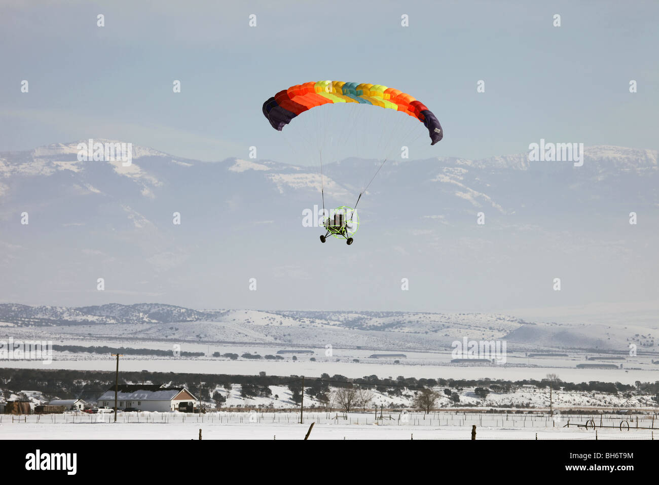 Powered parachute flying over rural farms. Multi colored parachute ...