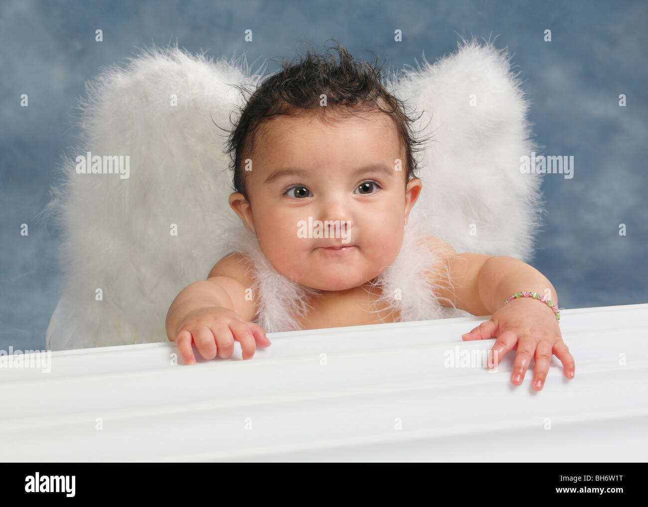 Hispanic baby girl with funny look on her face and wearing angel wings in a studio Stock Photo