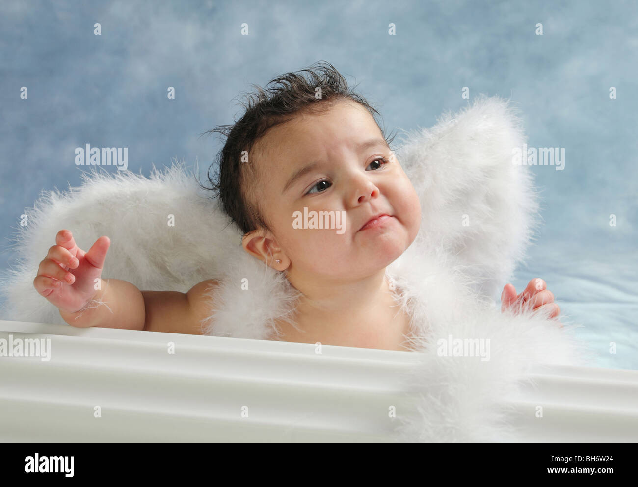 Hispanic baby girl with sad on her face and wearing angel wings in a studio Stock Photo