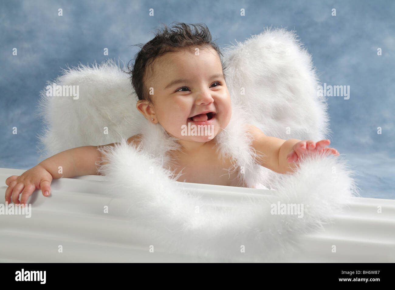 Hispanic baby girl with big smile look on her face and wearing angel wings in a studio Stock Photo