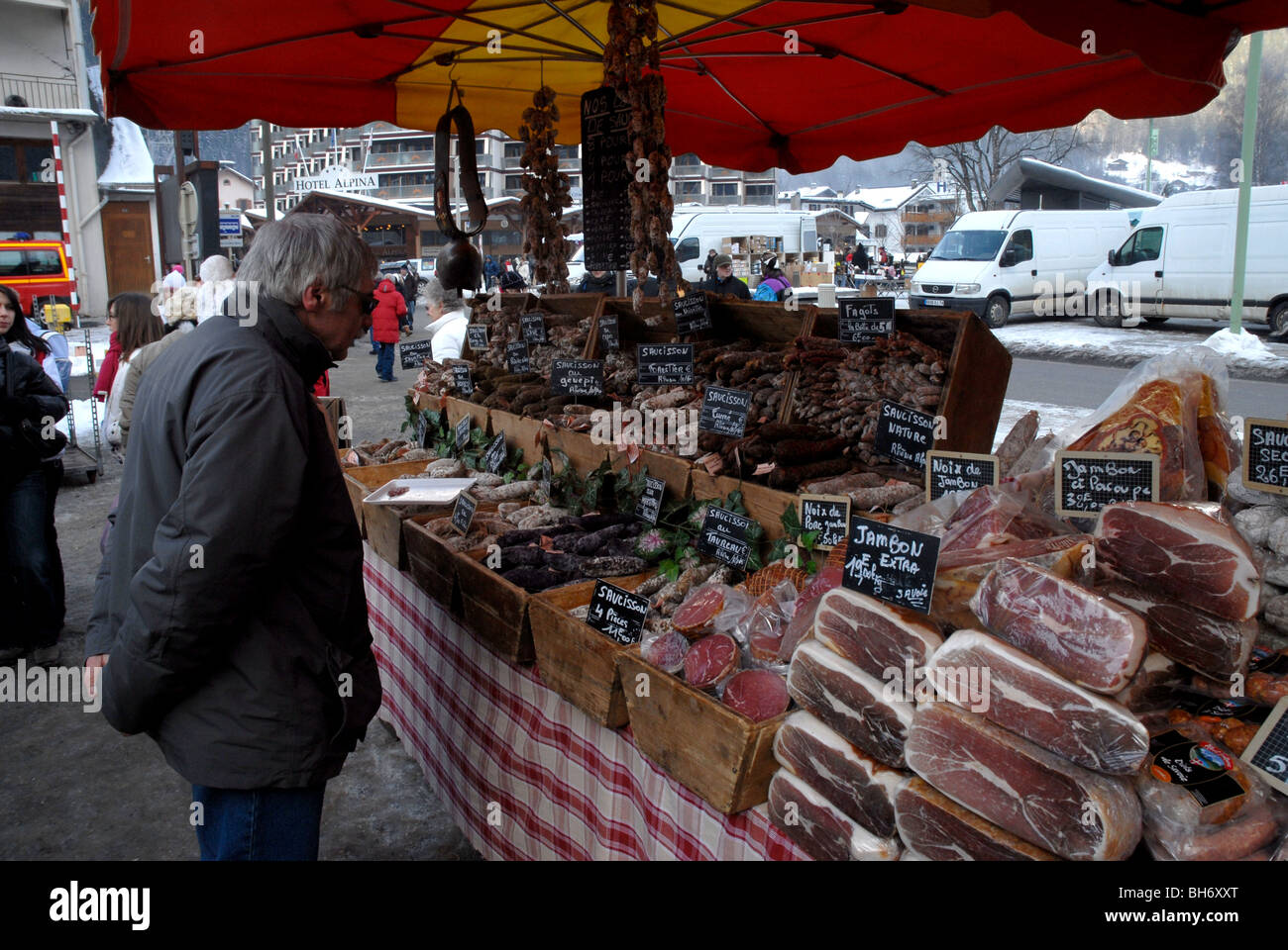 Man looking at salamis and hams on display at weekly farmers market ,Chamonix, Mont Blanc, France Stock Photo