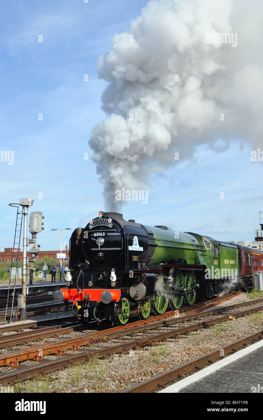 A1 Peppercorn class "Tornado" steam locomotive pulling out of a station with dramatic steam clouds in the sun. Stock Photo