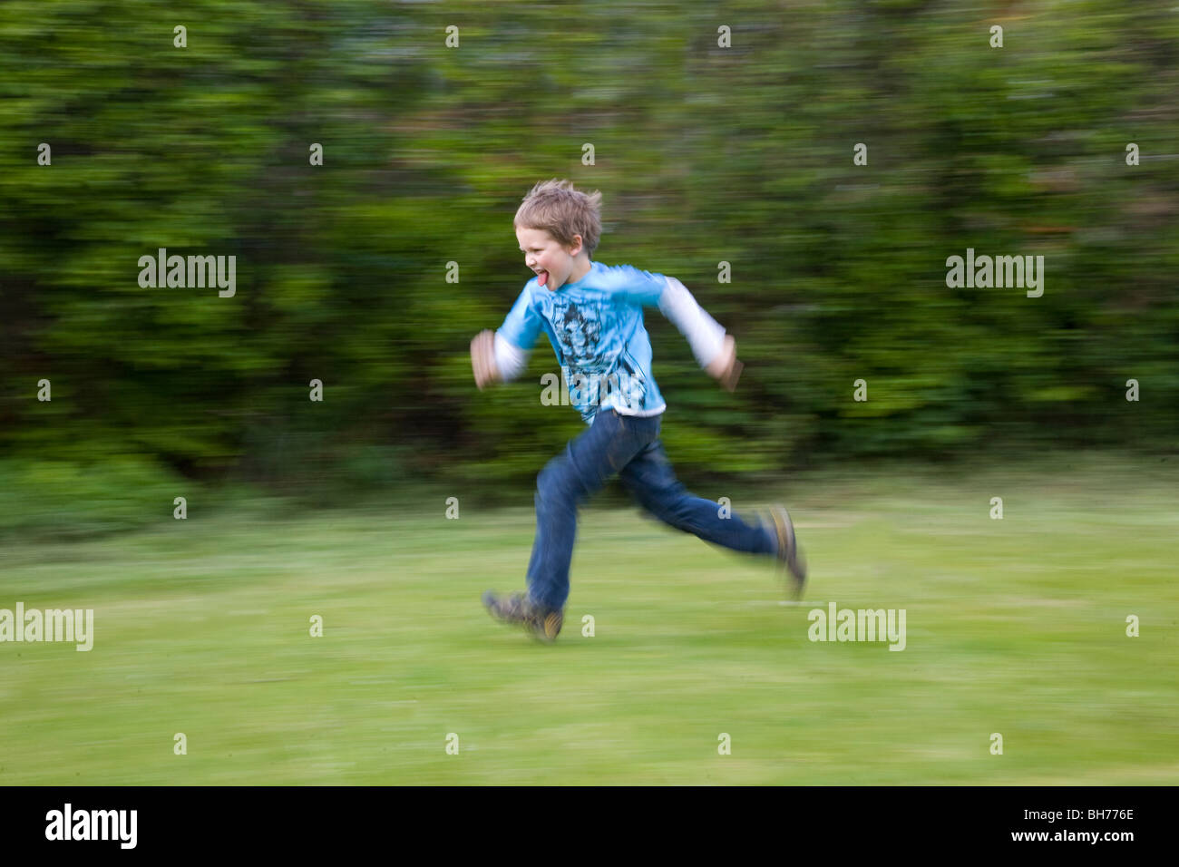 Young boy running flat out on grass with motion blur Stock Photo Alamy