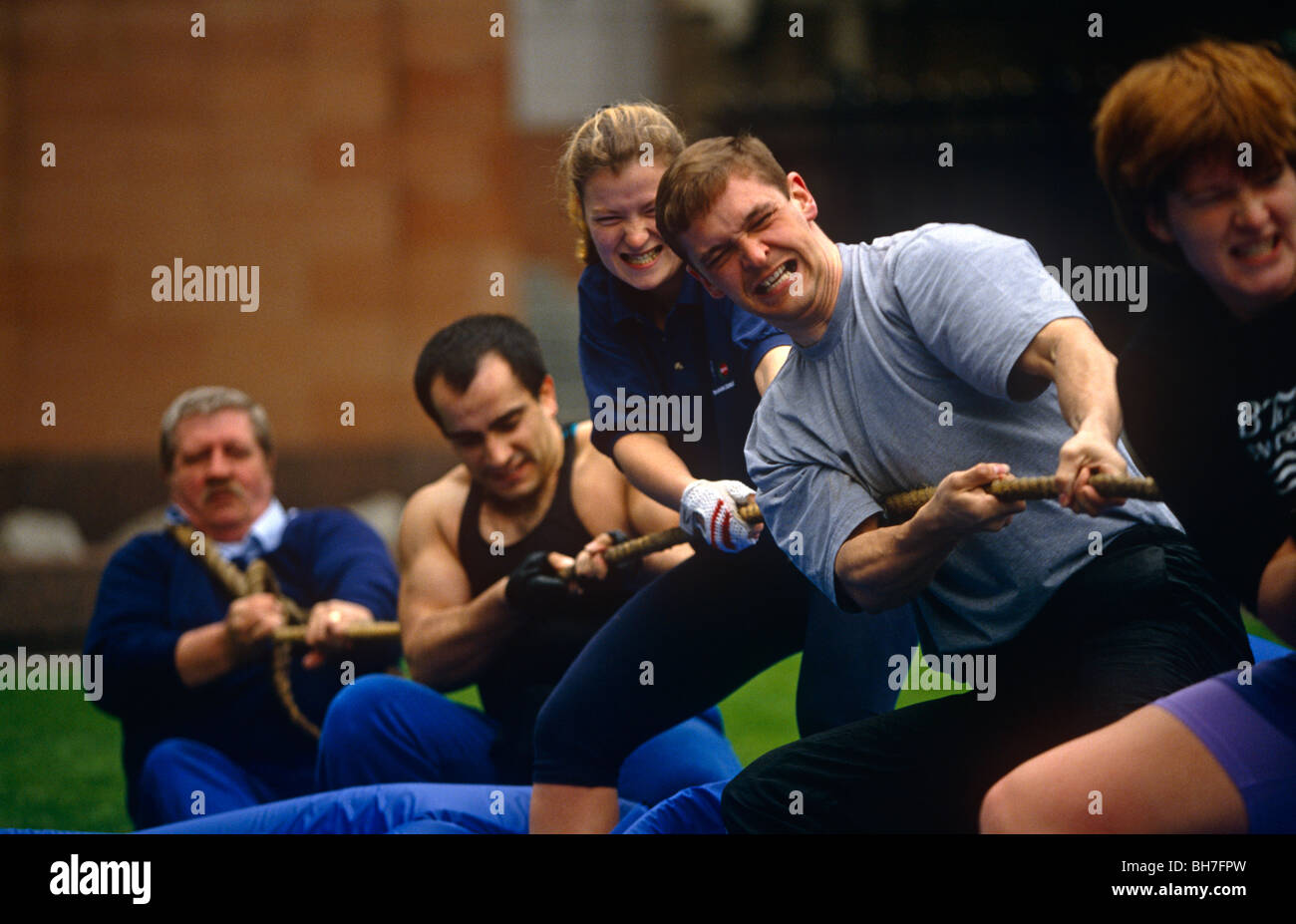 A tug of war team grit their teeth while having fun during a gym's lunchtime promotion in Broadgate. Stock Photo