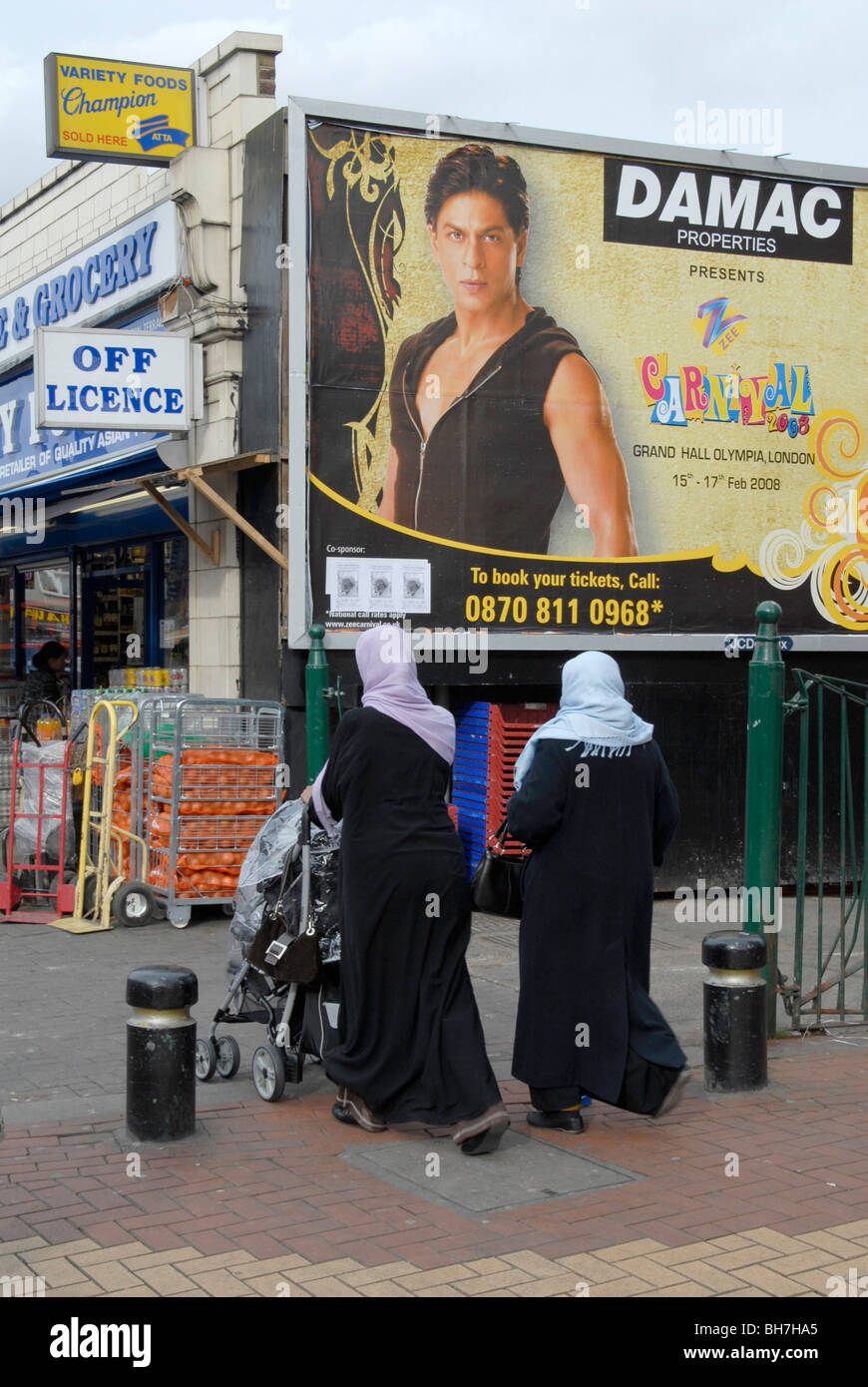 UK. Muslim shoppers in the streets of West Ham, London, with posters of Bollywood superstar Shahrukh Khan Stock Photo