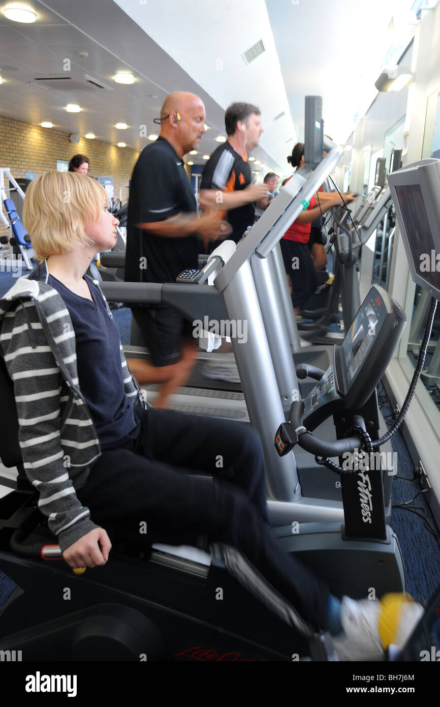 A young woman works out on the rowing machine in a crowded gym, Stock Photo