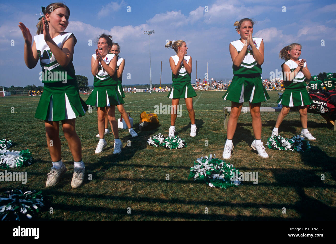 Young cheerleaders jump off the ground together during a Saturday morning High School football match in Mount Joy, Pennsylvania. Stock Photo