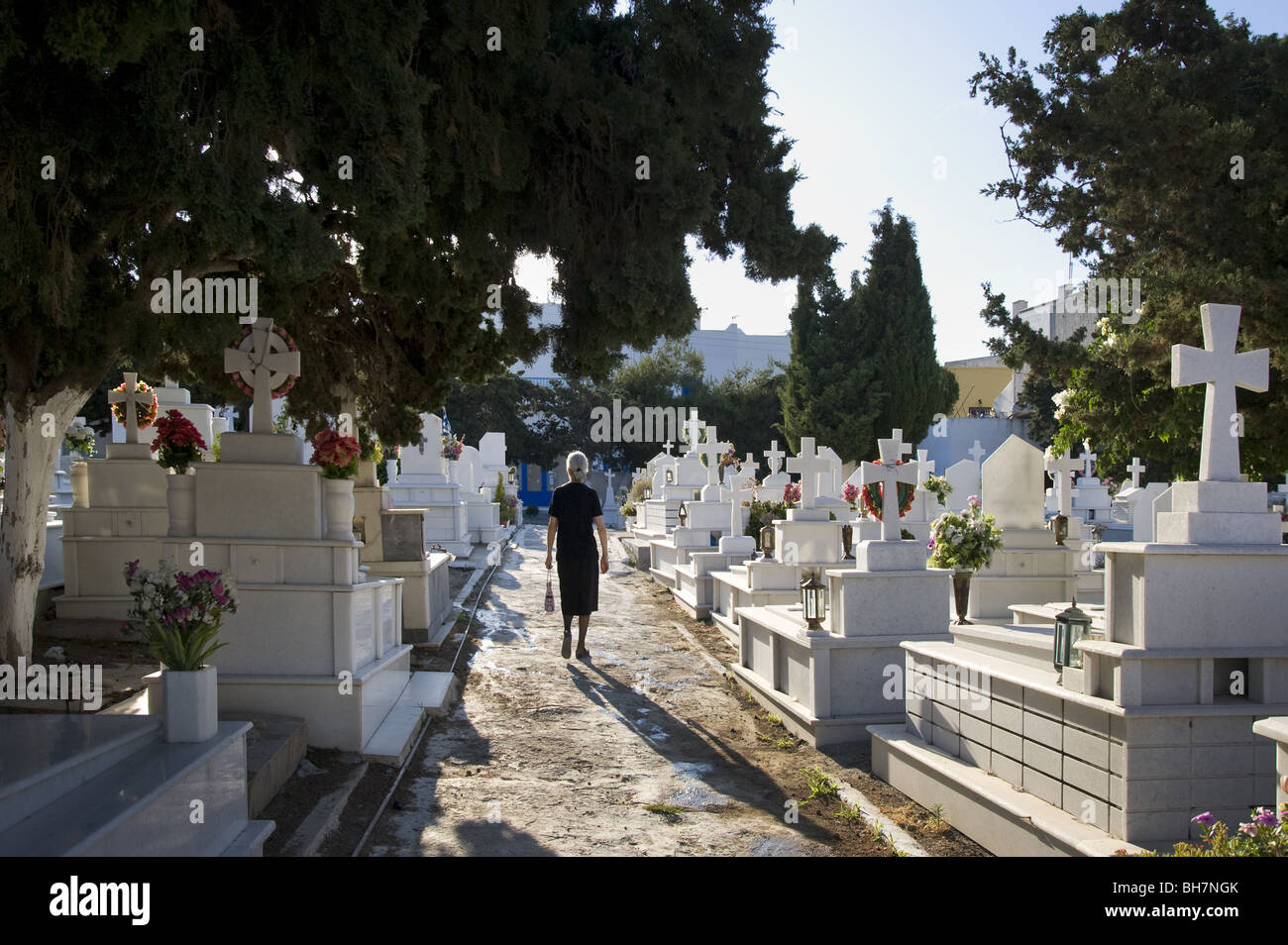 Greek woman walking on cemetery path between graves, Naxos, Greece. Stock Photo