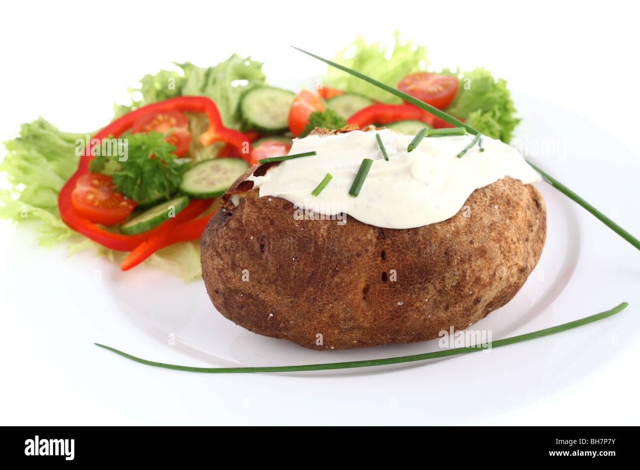 A baked russet potato, topped with cream cheese and chives and served