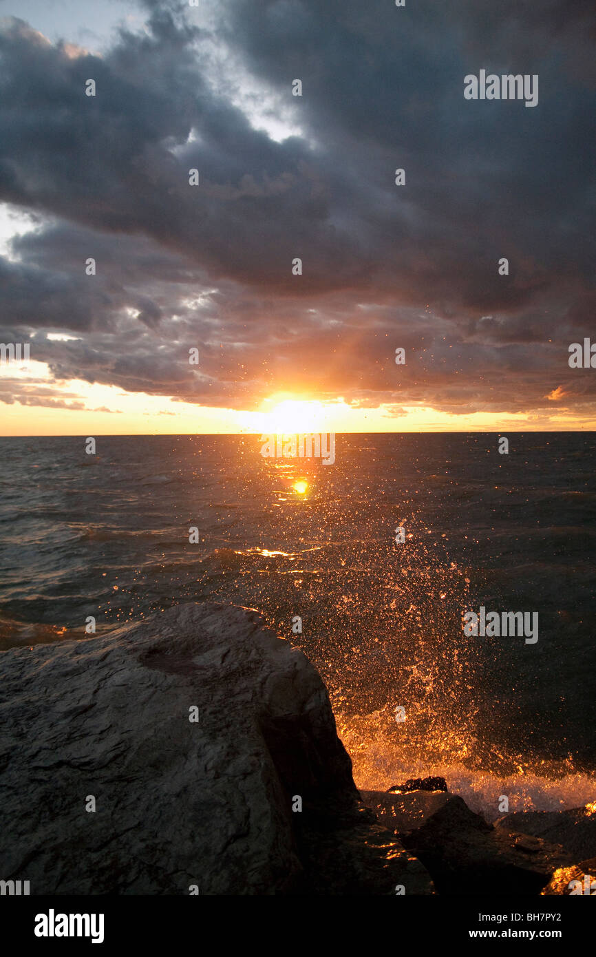 Waves splashing rocks at sunset Stock Photo